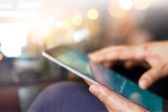 Nahansicht von Tablet, gehalten von einer sitzenden Person